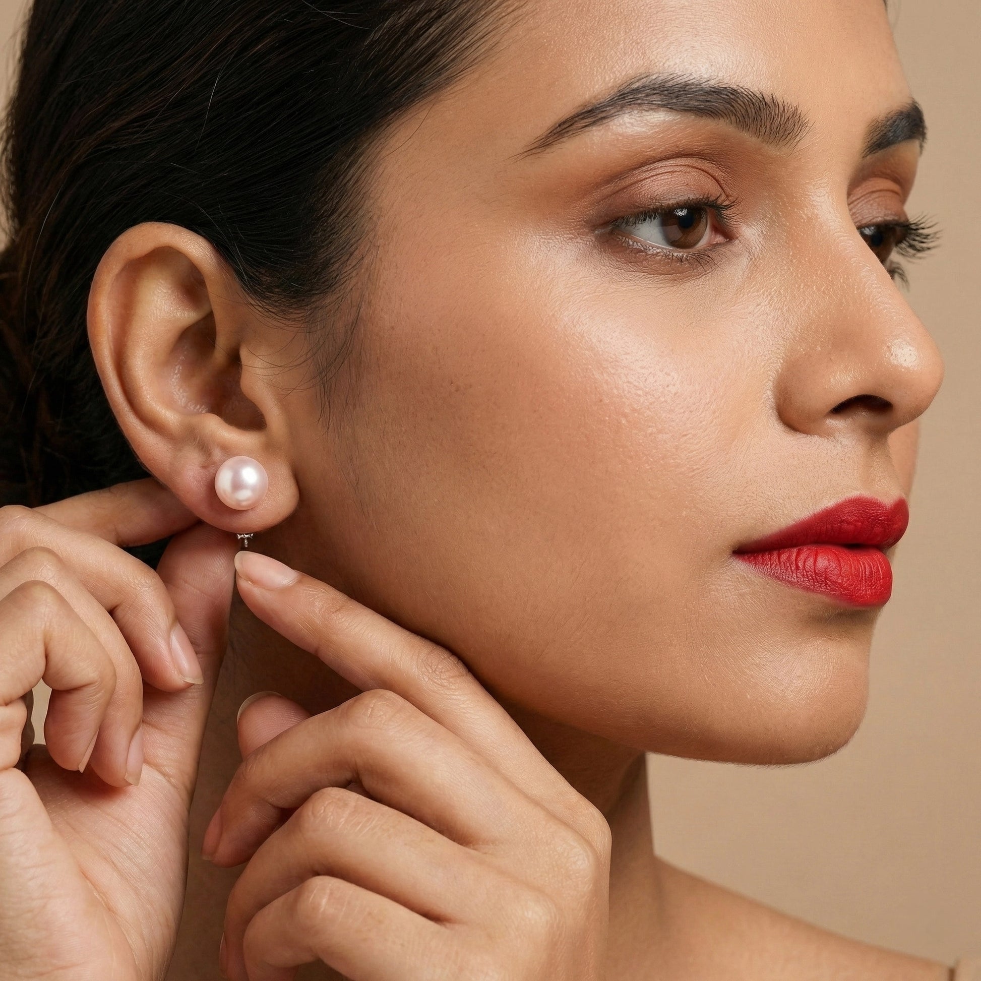 Close-up of a woman wearing a pearl earring against a beige background
