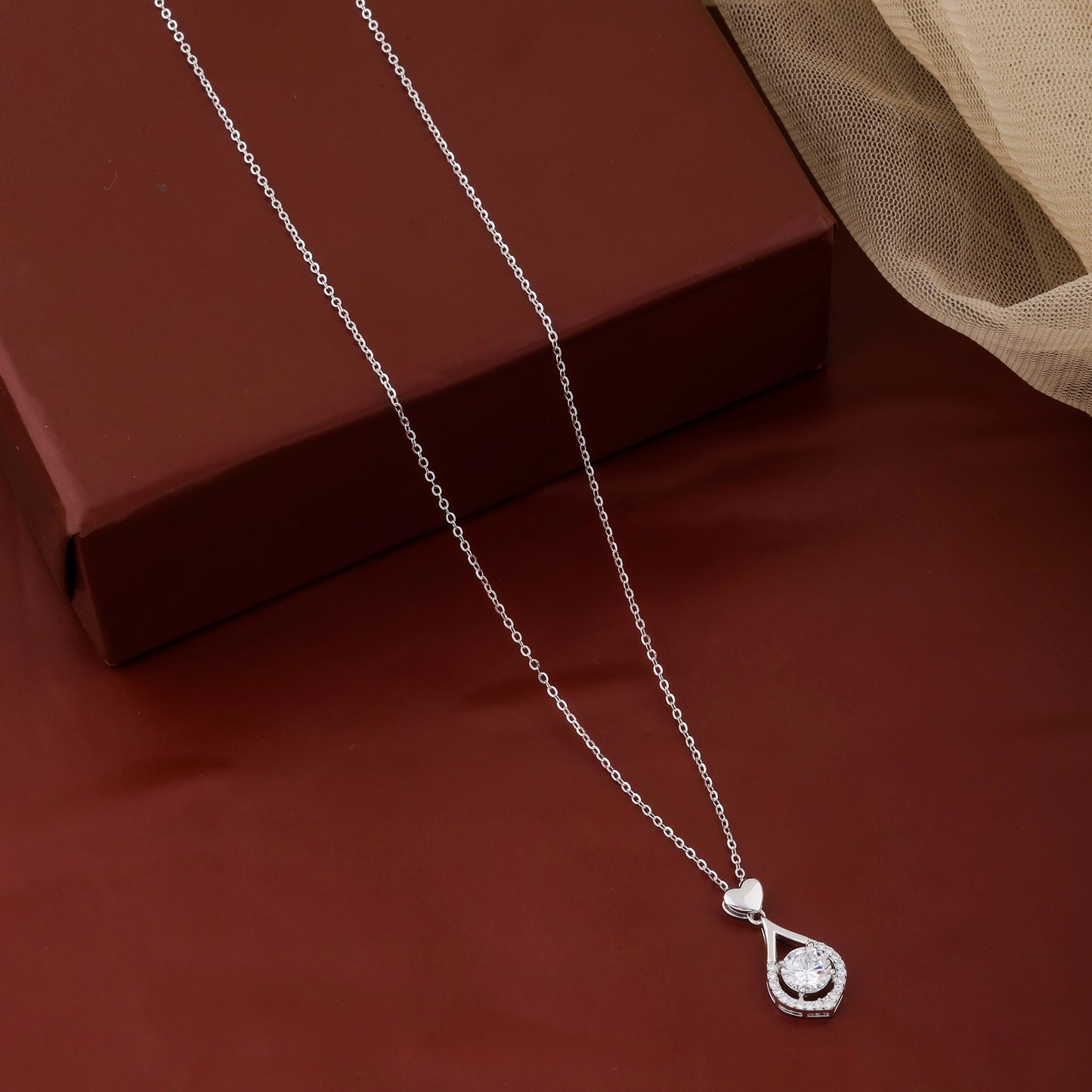 Silver necklace with a pendant on a red surface