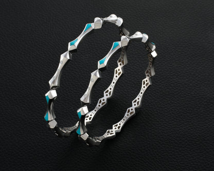Silver hoop earrings with turquoise accents on a black textured background