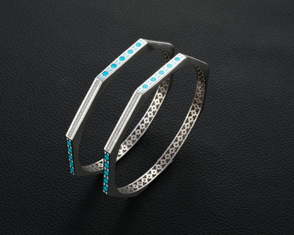 Silver hoop earrings with turquoise stones on a black textured background