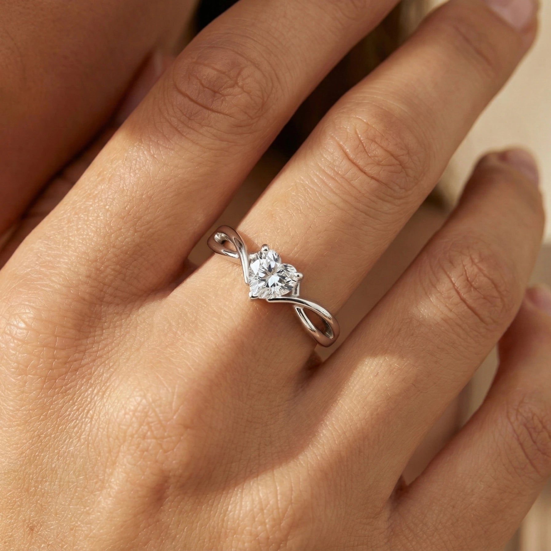 Silver heart-shaped diamond ring on a hand