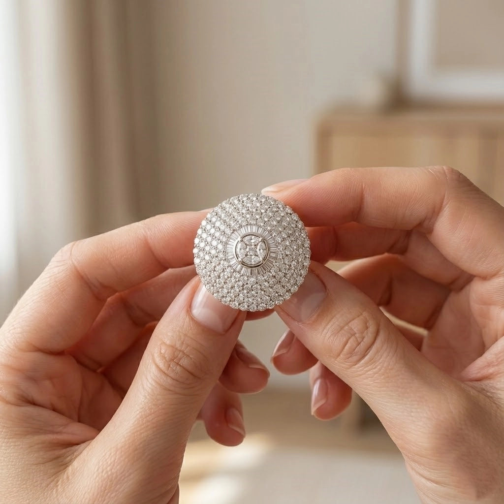 Silver jewelry box with intricate design held by hands against a neutral background