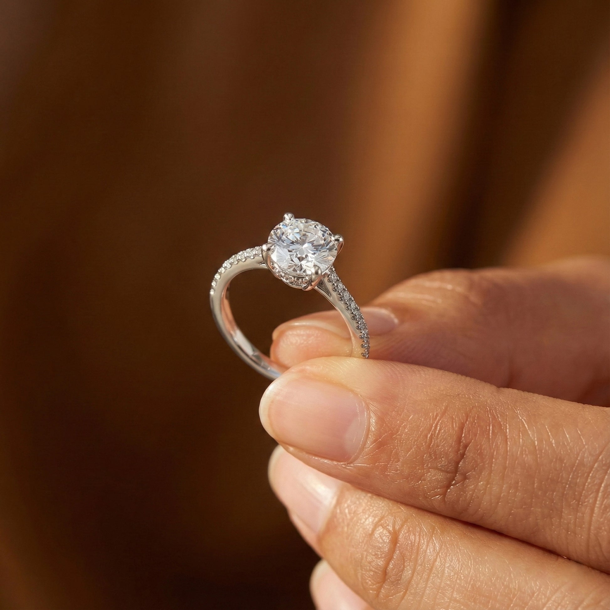 Diamond ring held in a hand with a blurred background