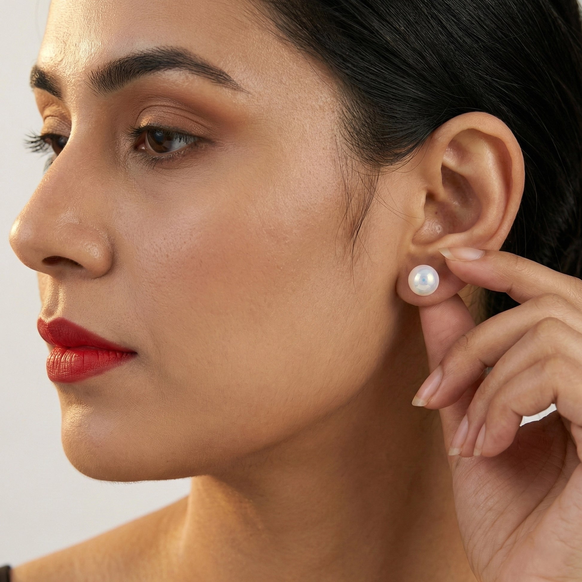 Minimalist pearl stud earrings photographed in soft studio lighting