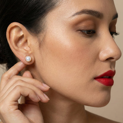 Classic white pearl studs arranged side by side on a dark backdrop