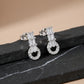 Pair of silver earrings with gemstones on a black stone surface