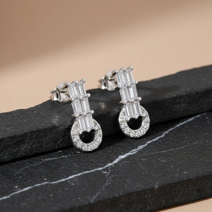 Pair of silver earrings with gemstones on a black stone surface