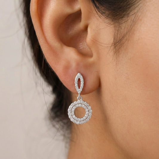 Close-up of a silver earring worn by a person with a neutral background