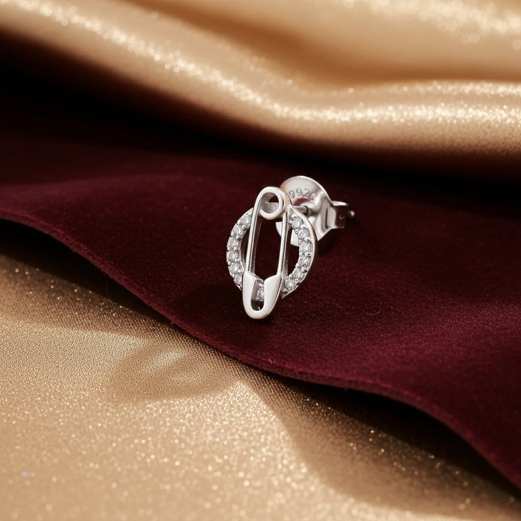 Silver earring on a textured fabric background