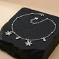 Silver anklets with snowflake charms on a dark stone surface