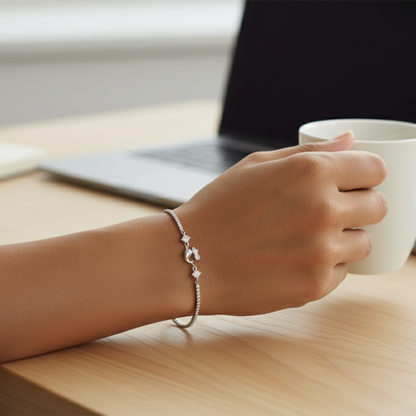 Hand holding a white mug on a wooden table with a laptop in the background