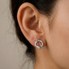 Close-up of an ear wearing a silver earring with a neutral background