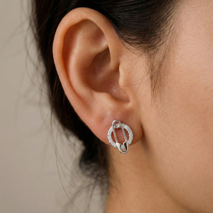 Close-up of an ear wearing a silver earring with a neutral background
