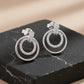 Pair of silver hoop earrings with embedded stones on a dark surface