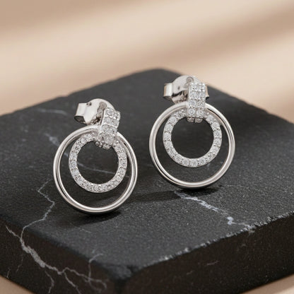 Pair of silver hoop earrings with embedded stones on a dark surface